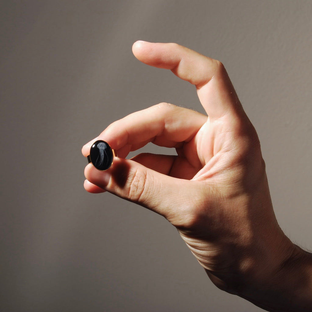 dita che tengono un anello ovale con micro medusa marina inglobata sotto resina