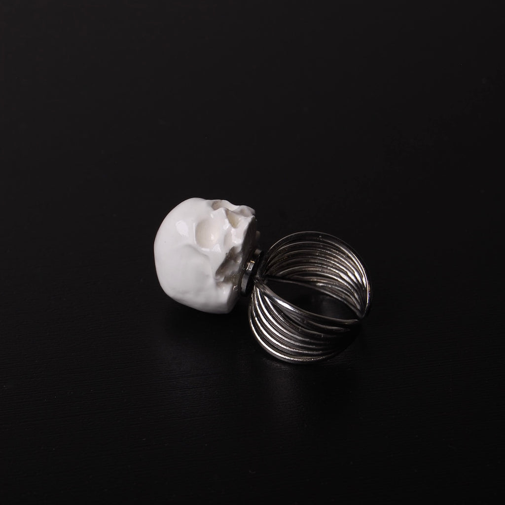 anello a banda larga con teschio bianco, poggiato su un piano nero
