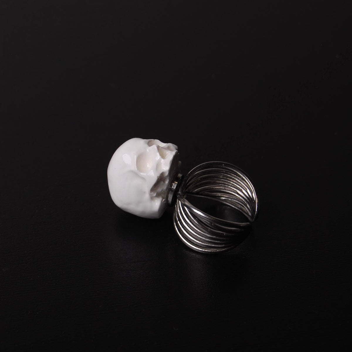 anello a banda larga con teschio bianco, poggiato su un piano nero