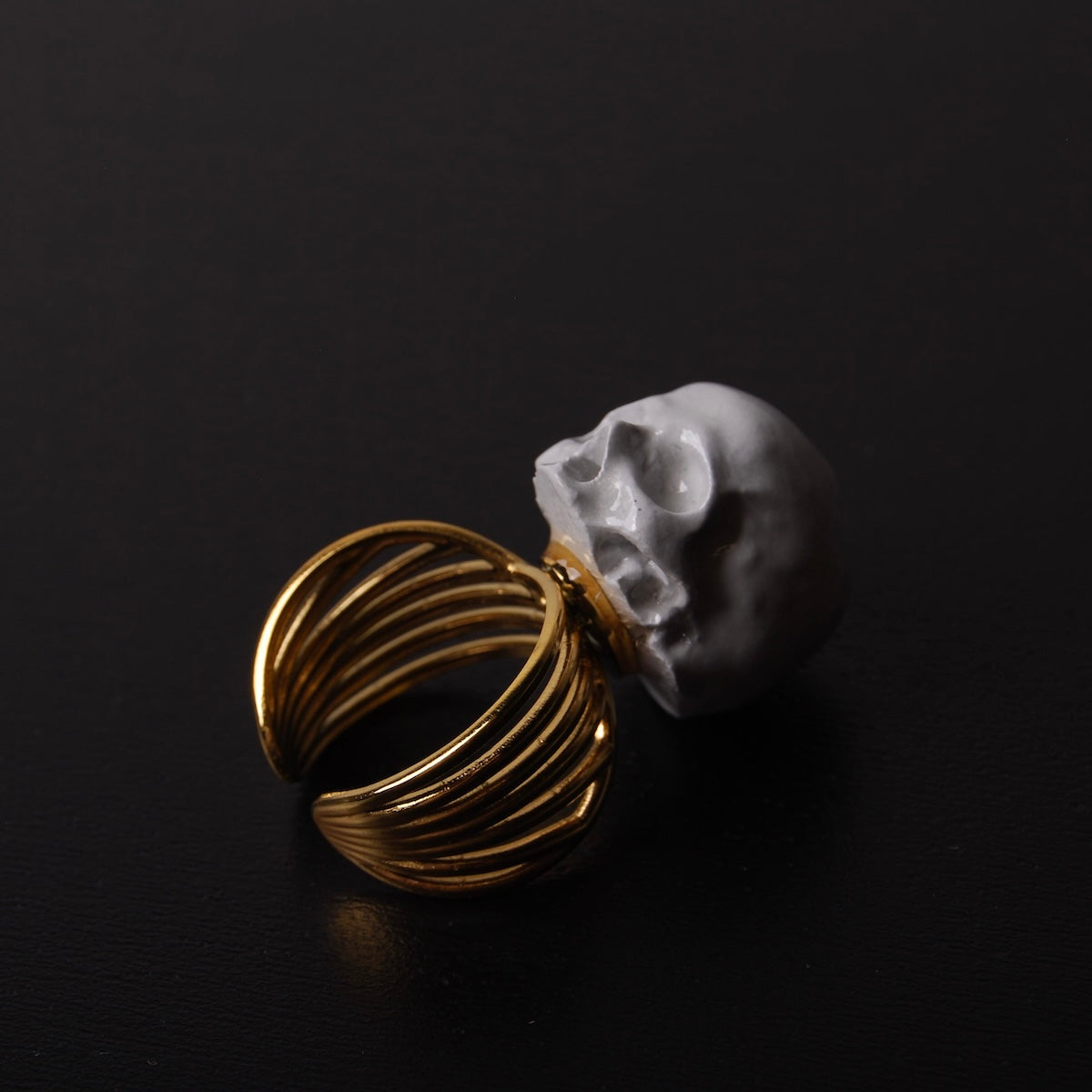 anello a banda larga con teschio grigio, poggiato su un ripiano nero