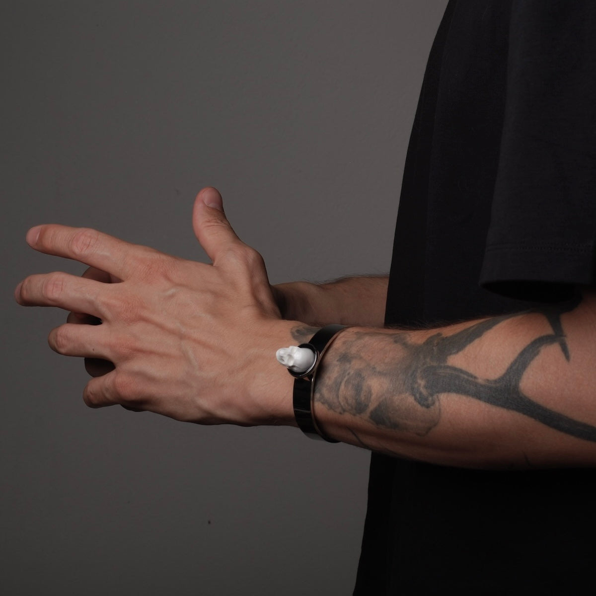 bracciale rigido con teschio indossato su braccio tatuato maschile