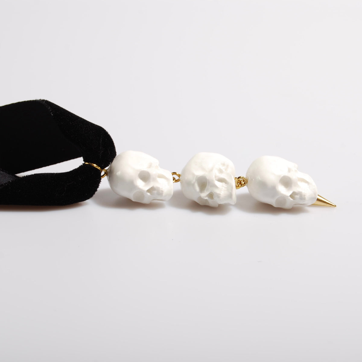 choker in velluto nero con fila di teschi e punta in acciaio placcato oro