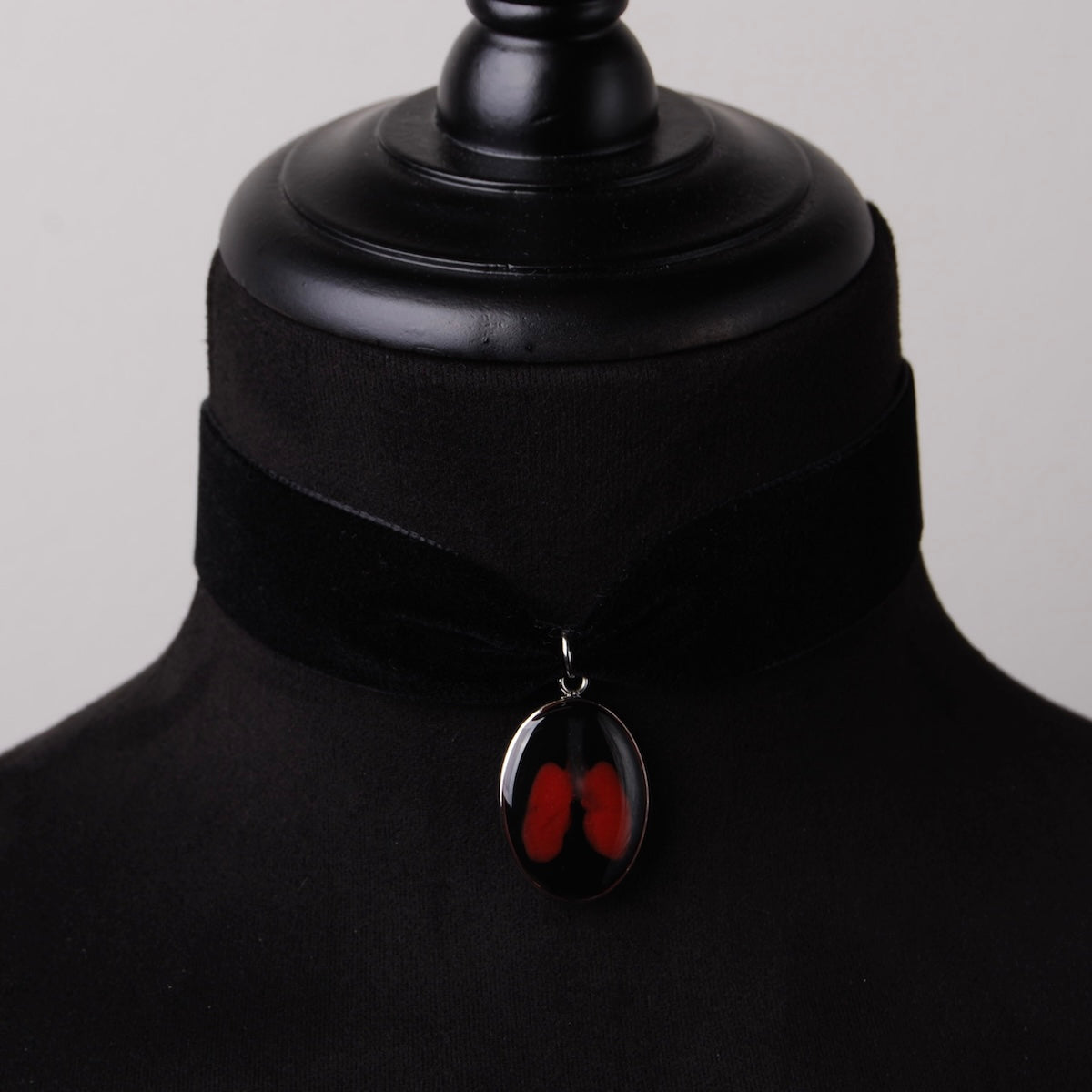 choker in velluto nero con pendente ovale con miniatura di polmoni, su busto espositivo in velluto