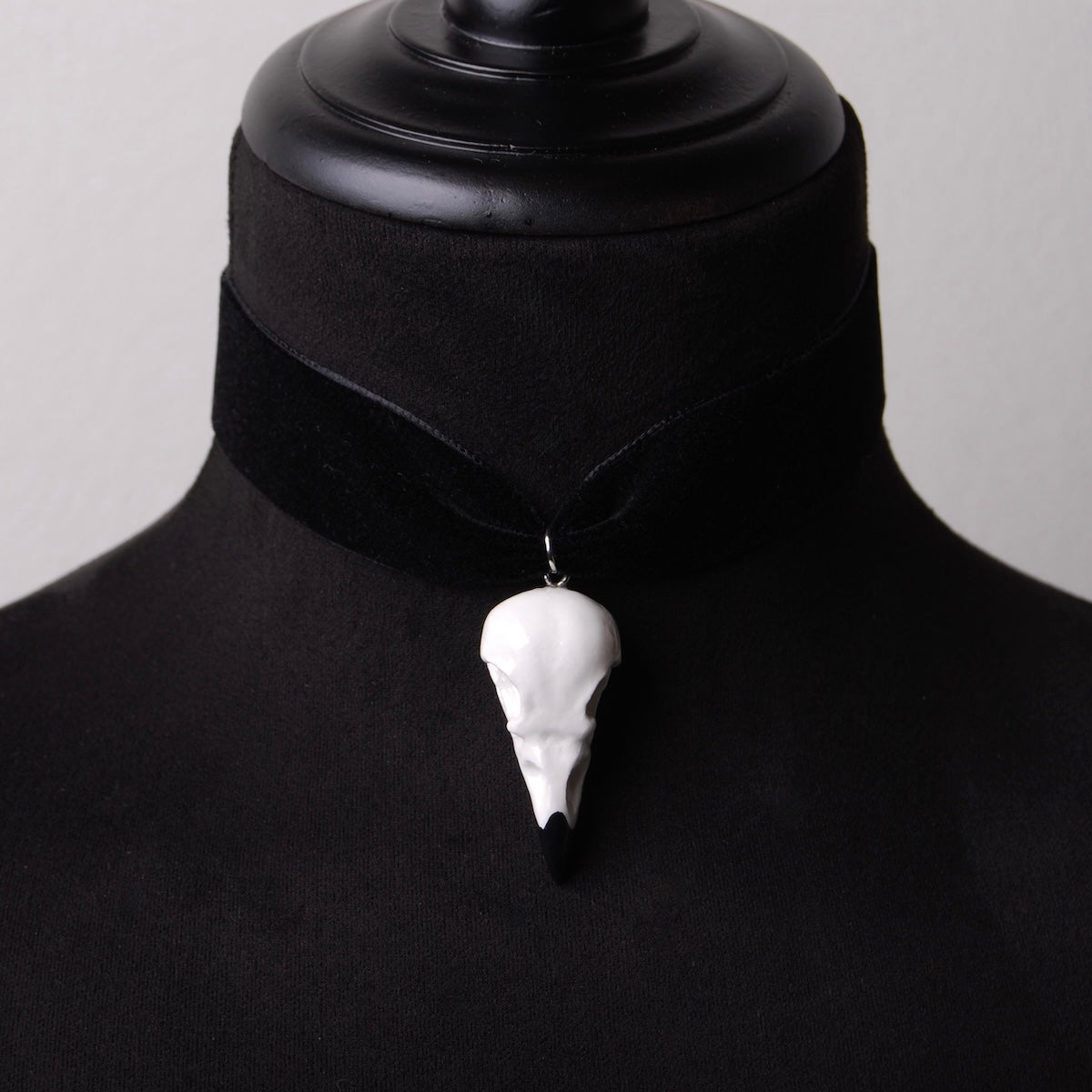 choker in velluto nero con pendente teschio di corvo indossato su busto espositivo