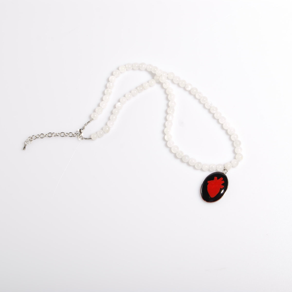 collana con sfere di pietra di luna e pendente centrale ovale con cuore anatomico, vista dall'alto