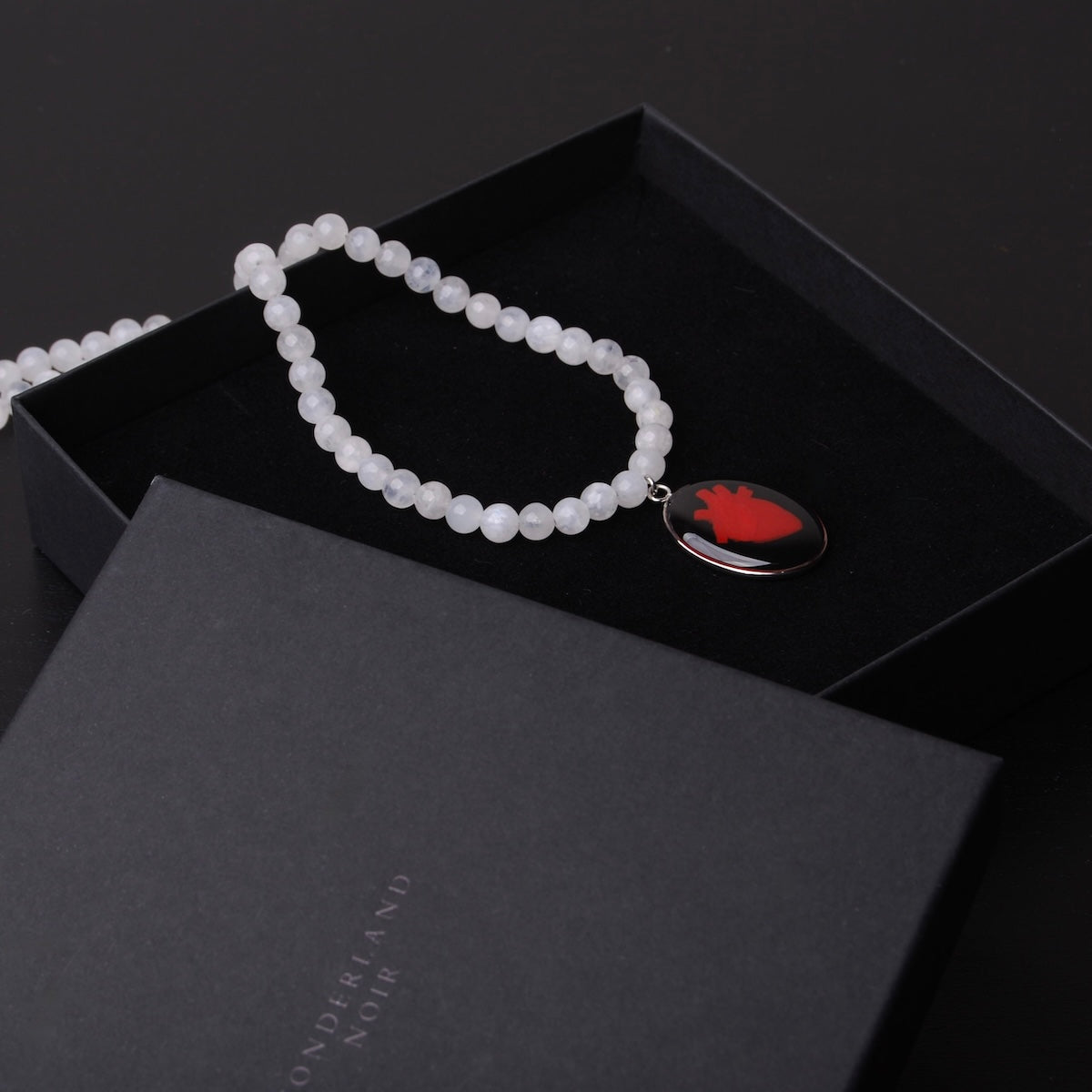 collana con sfere di pietra di luna e pendente centrale ovale con cuore anatomico dentro ad una scatolina nera