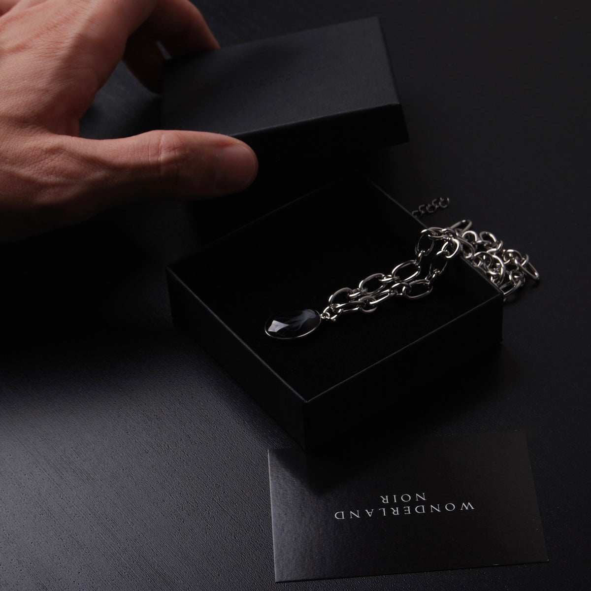 mano che chiude una scatolina con collana catena in acciaio con pendente medusa marina