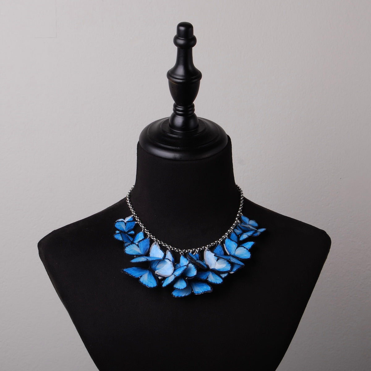 collana con sciame di farfalle blue morpho su busto espositivo, vista frontale