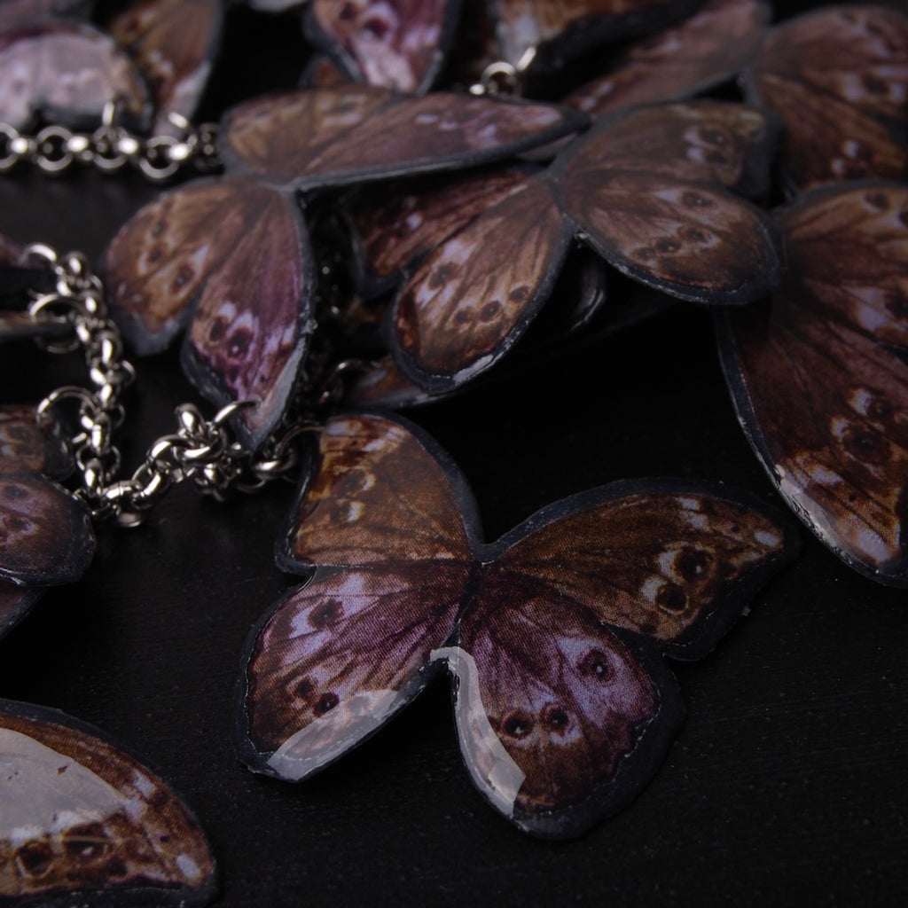 dettaglio di pendente farfalle blue morpho di una collana, vista del retro color marrone