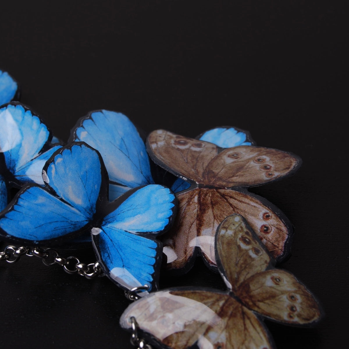 collana sciame di farfalle blu, alcune girate dalla parte marrone delle ali, dettaglio ravvicinato
