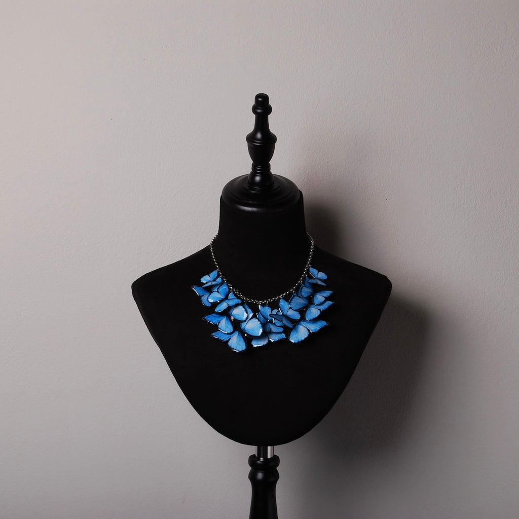 collana sciame di farfalle blu su espositore in velluto nero