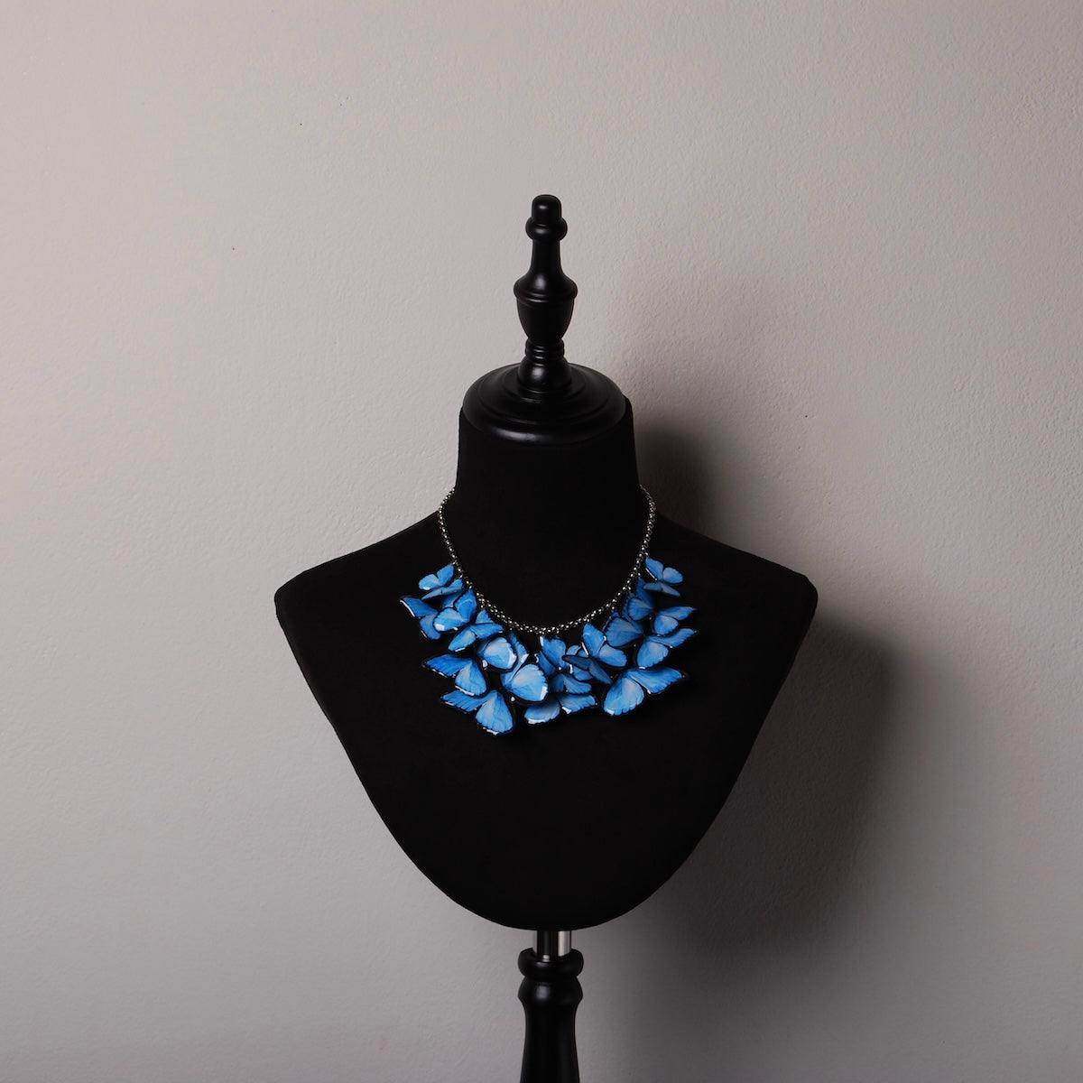 collana sciame di farfalle blu su espositore in velluto nero