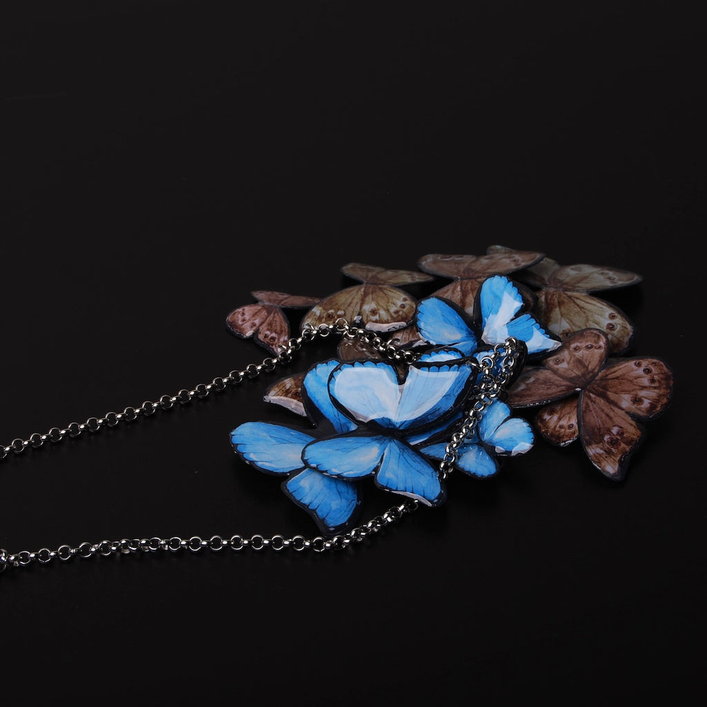 collana sciame di farfalle blu, alcune girate dalla parte marrone delle ali