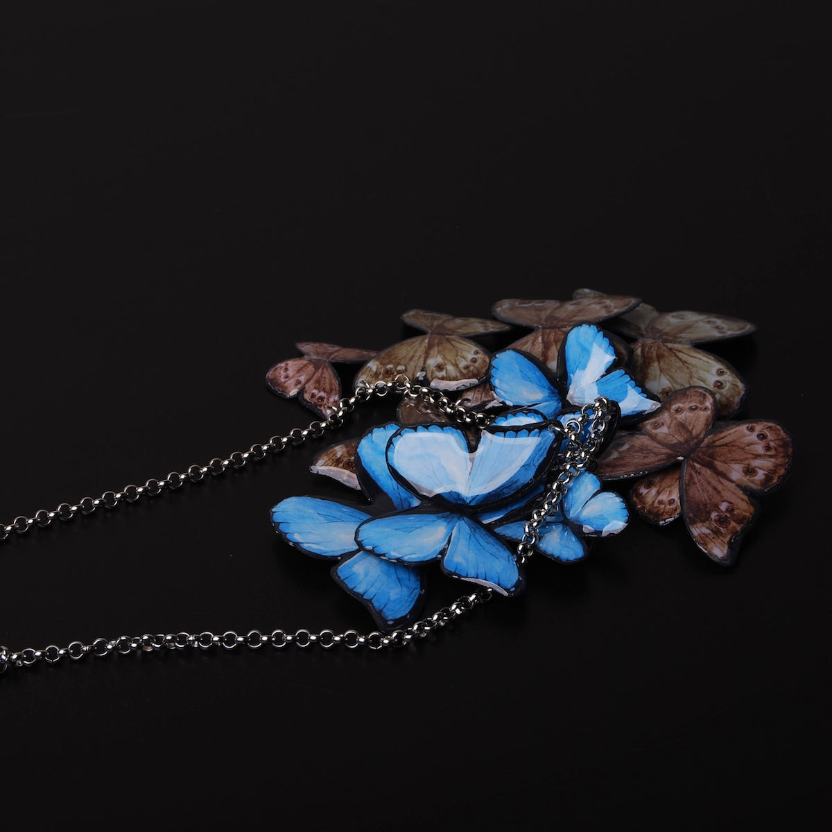 collana sciame di farfalle blu, alcune girate dalla parte marrone delle ali