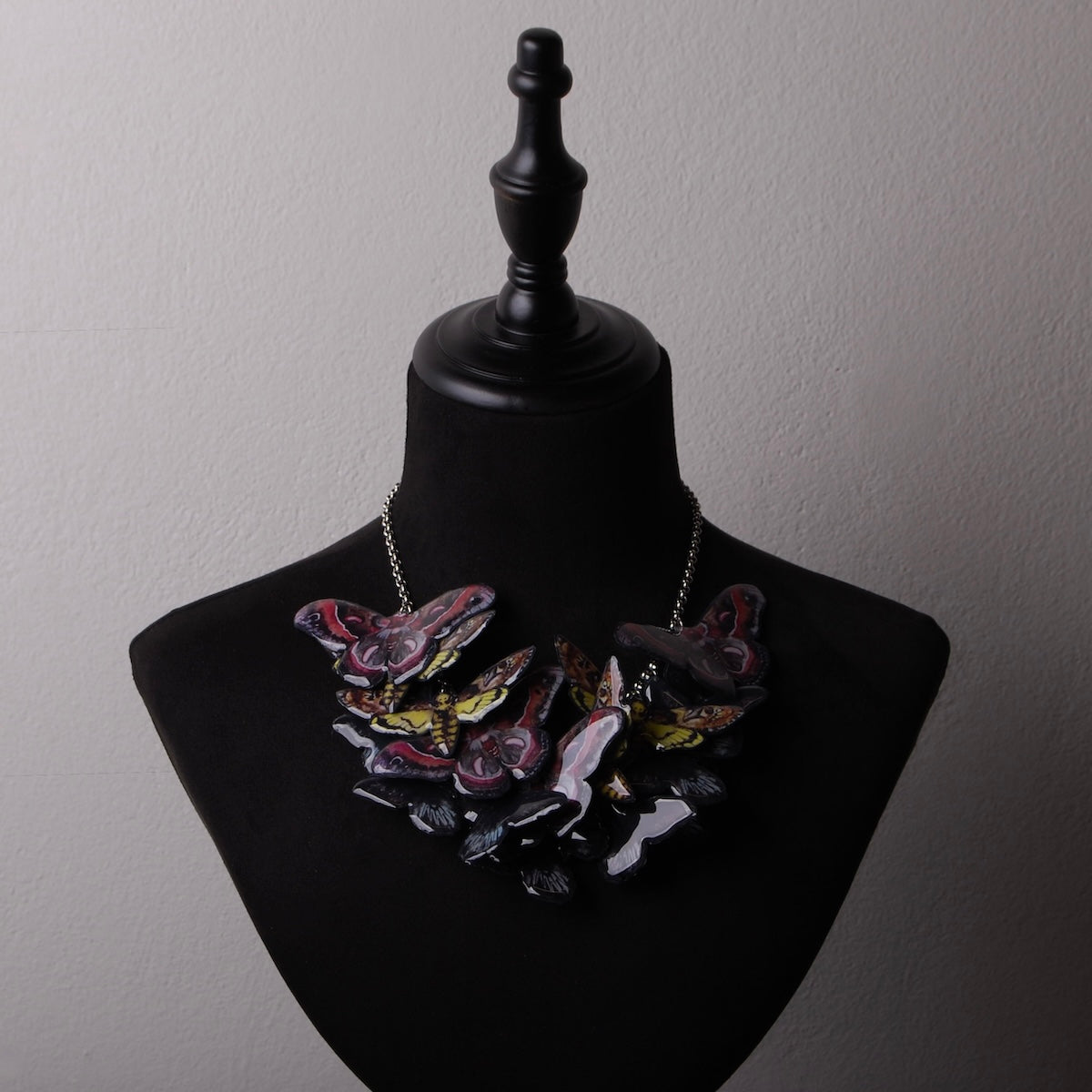 collana sciame di farfalle e falene su busto espositivo
