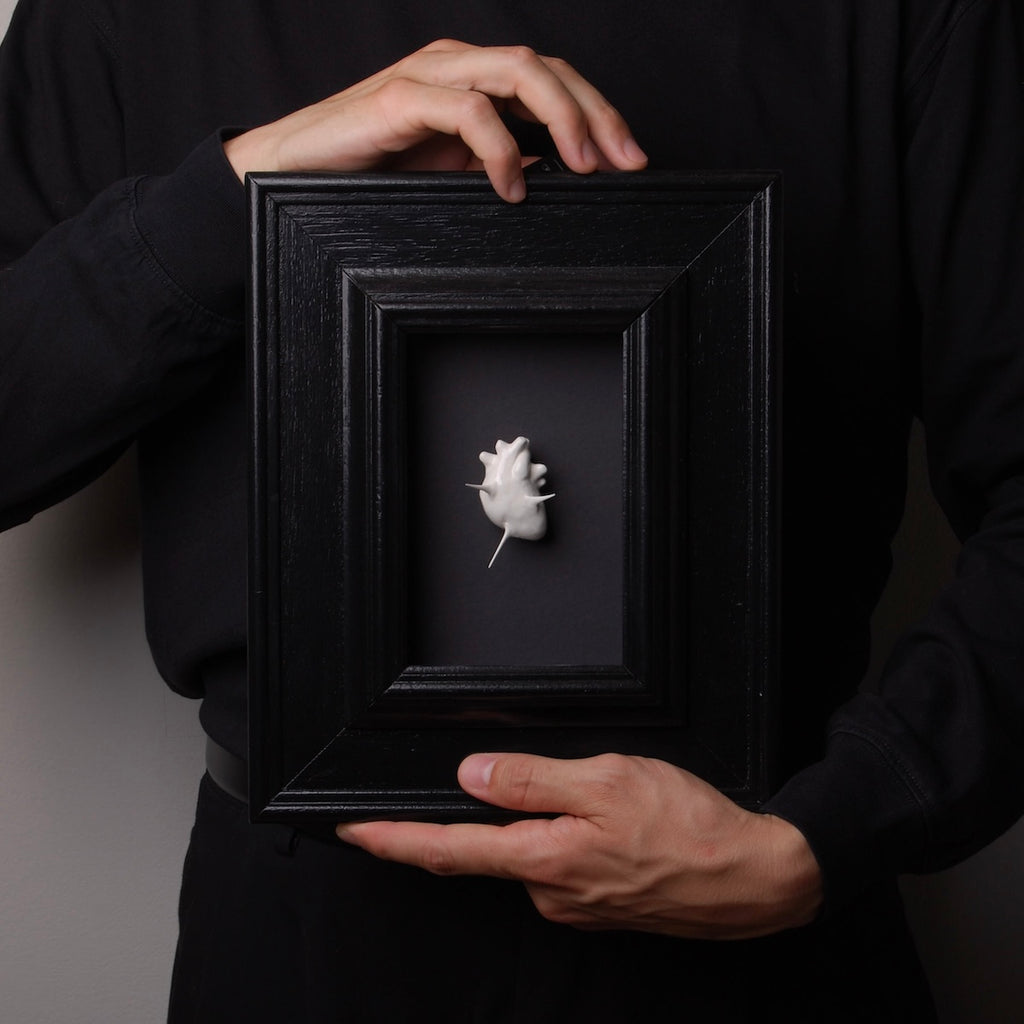 mani che tengono un quadro con cuore anatomico spinato