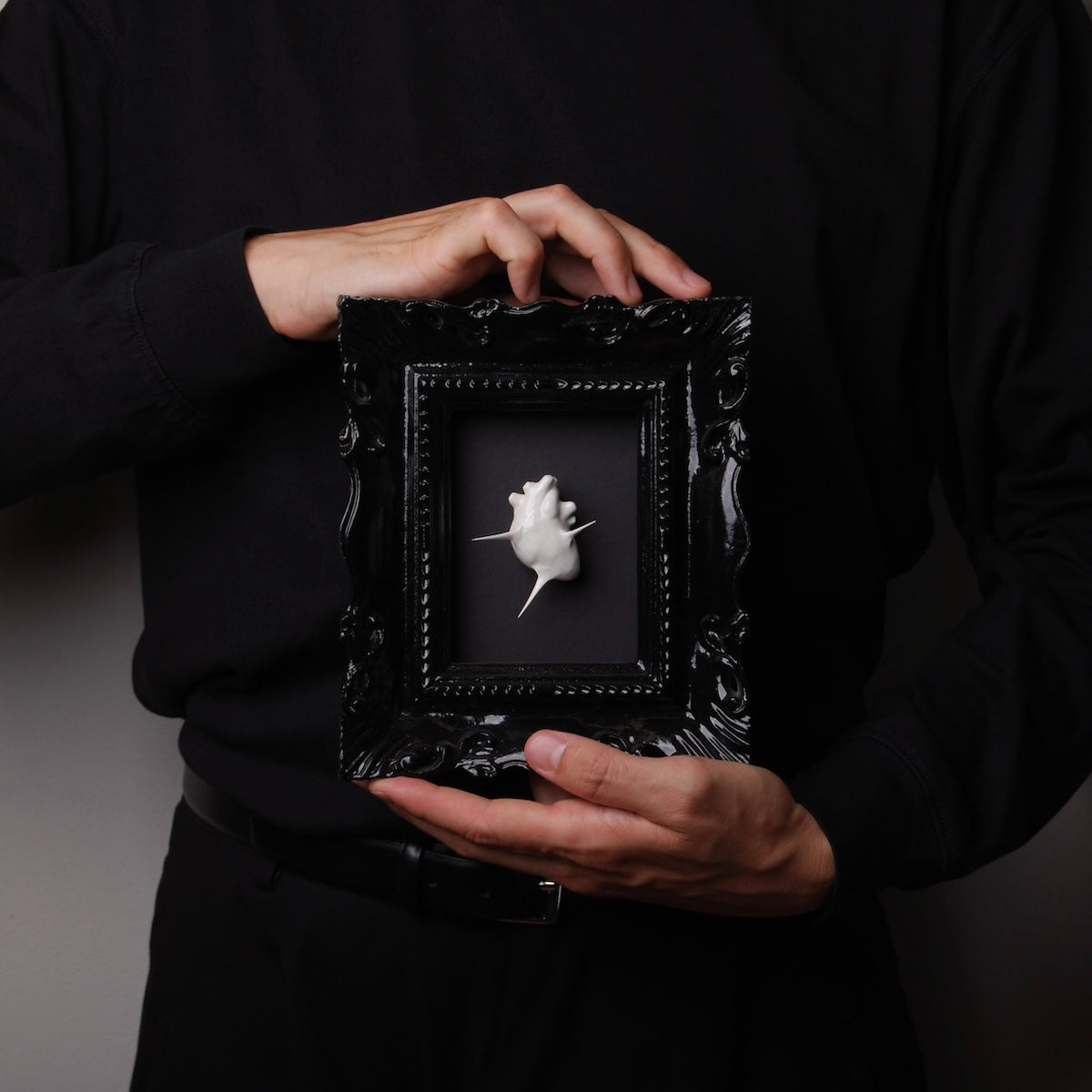 mani che tengono un quadro cornice gotica con cuore spinato bianco