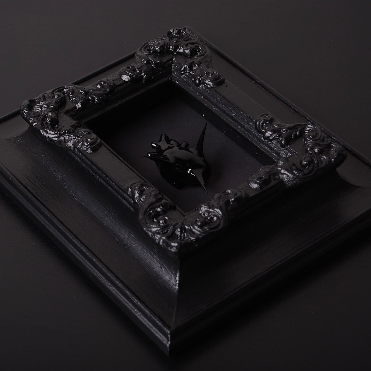 un quadro con cornice antica con cuore anatomico spinato nero, vista 3/4
