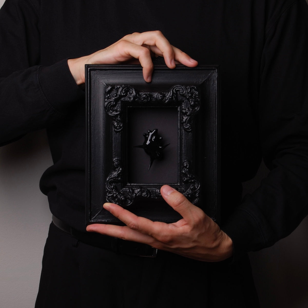 mani che tengono un quadro con cornice antica con cuore anatomico spinato nero