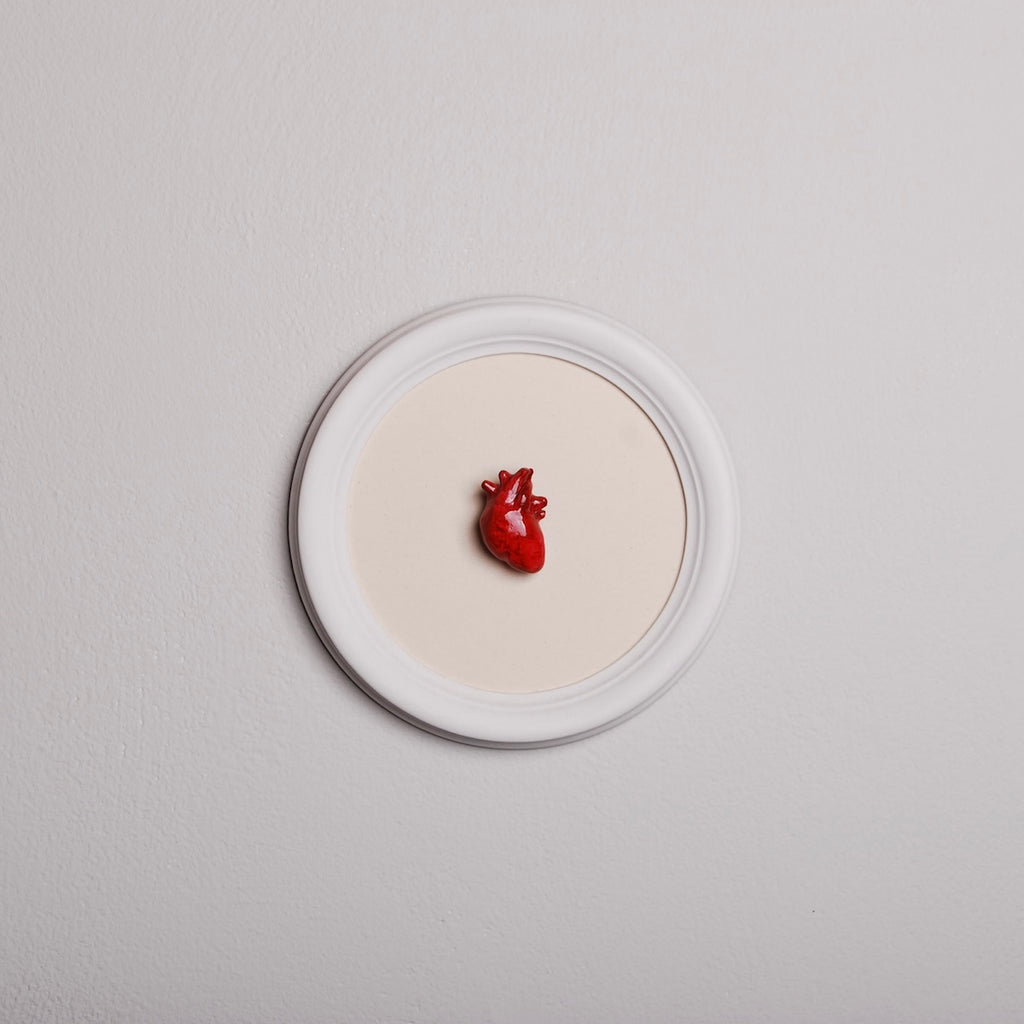 quadretto rotondo con cornice bianca e cuore anatomico rosso