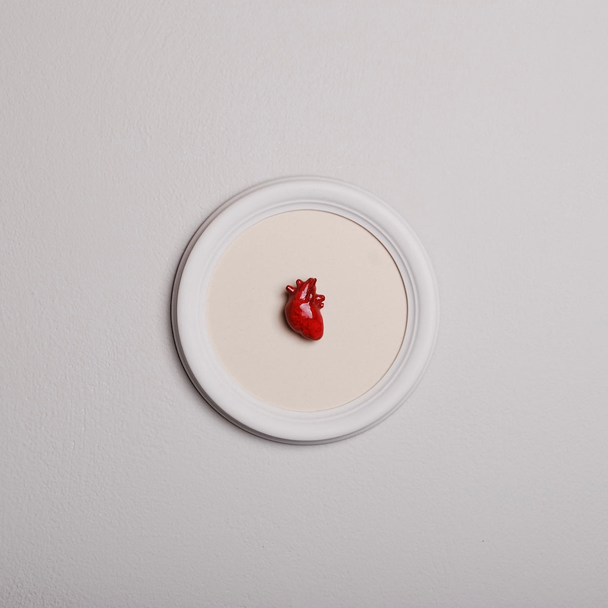 quadretto rotondo con cornice bianca e cuore anatomico rosso