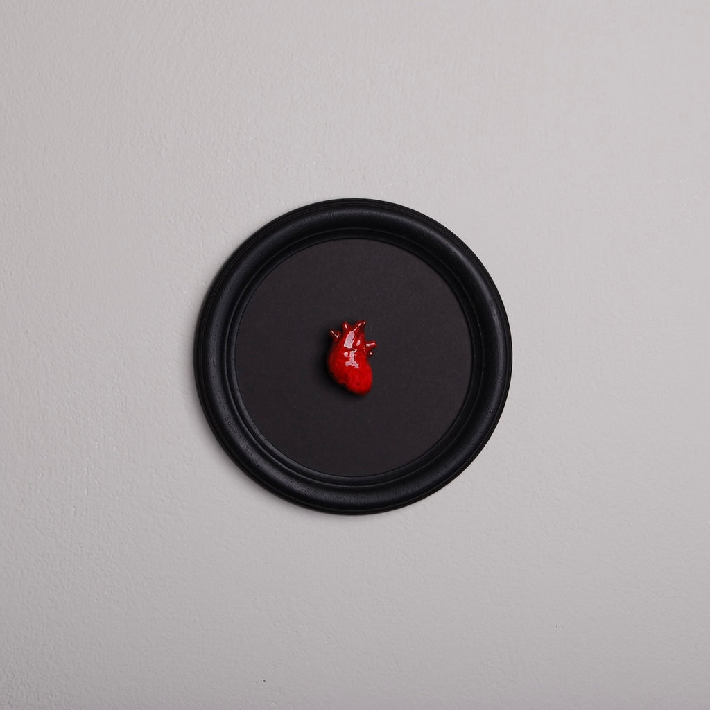 quadretto rotondo con cornice nera e cuore anatomico rosso
