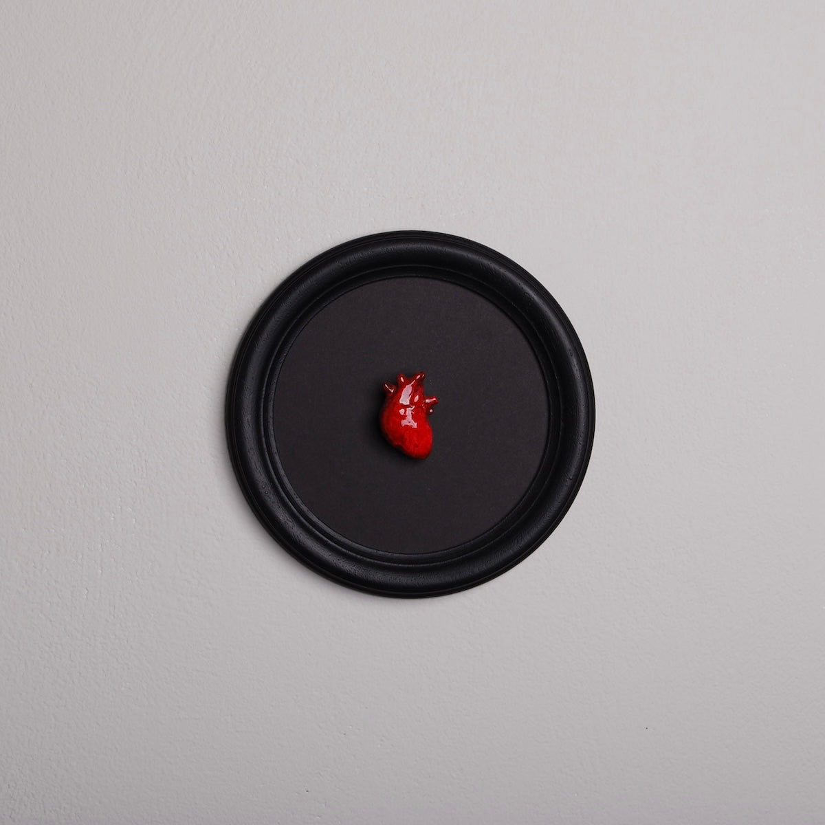quadretto rotondo con cornice nera e cuore anatomico rosso