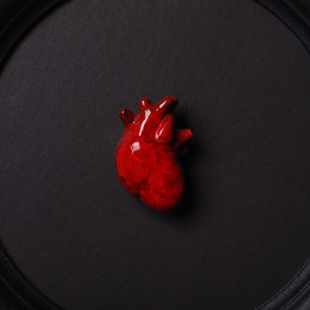 quadretto rotondo con cornice nera e cuore anatomico rosso, dettaglio del cuore centrale