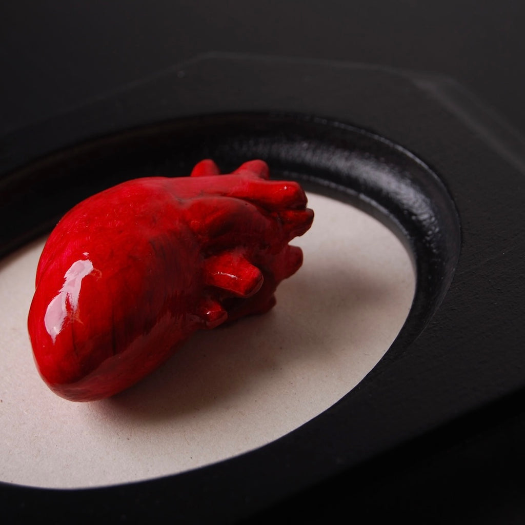 quadretto ottagonale con scultura cuore anatomico rosso al centro, dettaglio ravvicinato del cuore
