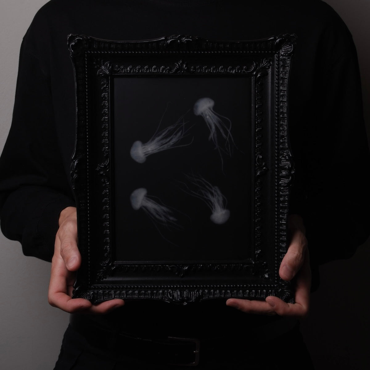quadro con sculture di meduse marine in cornice rettangolare intarsiata, tenuto tra due mani in verticale