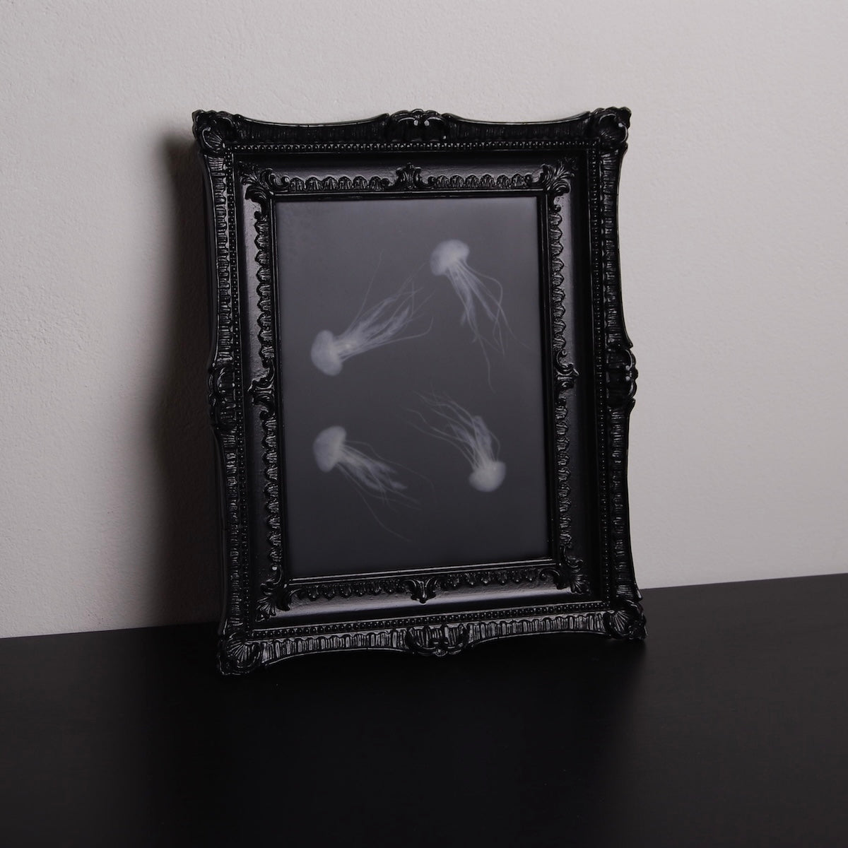 quadro con sculture di meduse marine in cornice rettangolare intarsiata, vista 3/4 verticale